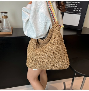 Détail du sac cabas en paille tissée avec motif floral évidé et bandoulière ethnique