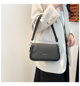 Detail of black woven leather shoulder bag featuring a silver metal buckle and wide strap