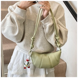 Detail of light green crescent croissant bag with textured finish and cute duck pendant