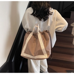 Rear view of khaki drawstring tote bag with off-white straps on casual grey hoodie