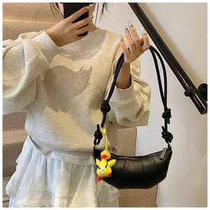 Detail of black crescent shoulder bag featuring textured leather and a yellow duck charm