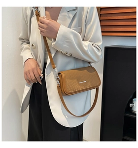 Brown crossbody bag featuring a woven texture flap styled with a white blazer