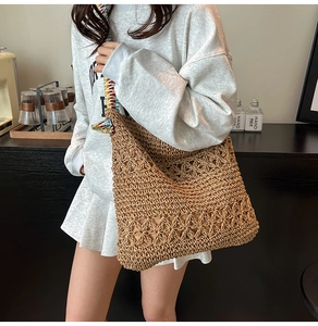 Détail du crochet floral ajouré sur un sac cabas en paille avec bandoulière ethnique