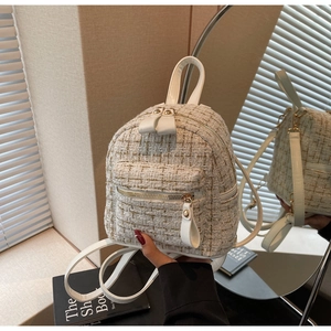 Détail de la texture en tweed avec fils dorés sur un mini sac à dos pour femmes