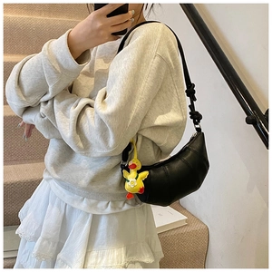 Detail shot of black pebbled leather crescent handbag featuring a yellow duck plush charm