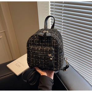 Vue macro de la texture en tweed d'un mini sac à dos avec fermetures éclair dorées