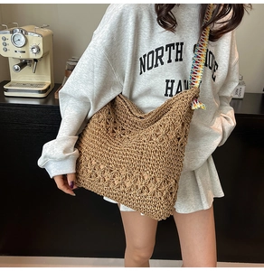 Détail d'un sac cabas en paille tissé avec une large bandoulière en tricot coloré