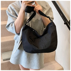 Détail d'un sac cabas noir avec broderie étoile et bandoulière réglable sur le côté