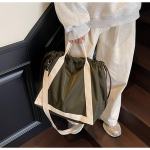 Detail of army green nylon tote bag with drawstring closure and cream woven strap