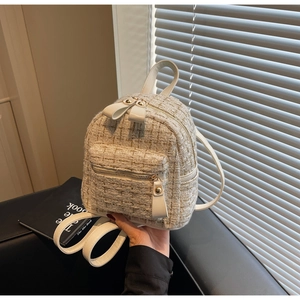 Gros plan d'un mini sac à dos en tweed blanc avec fils dorés et finitions en cuir
