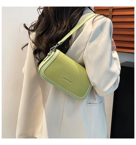 Detail of avocado green woven shoulder bag with silver hooks on white suit model