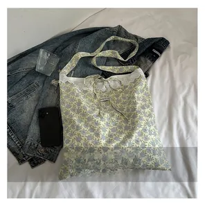 Détail du sac fourre-tout en toile florale avec dentelle blanche et nœud décoratif