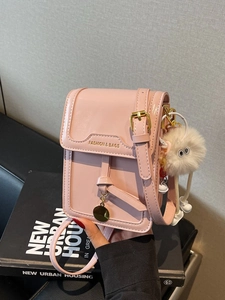 Pink glossy leather crossbody phone bag with metal logo and white furry pompom charm