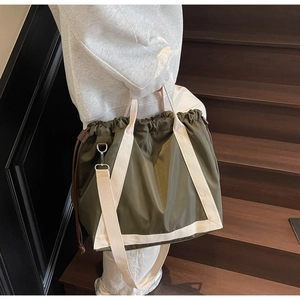 Detail of olive green drawstring tote with white canvas handles and silver hardware