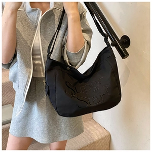 Détail du grand sac hobo noir avec embossage Super Star et bandoulière ajustable