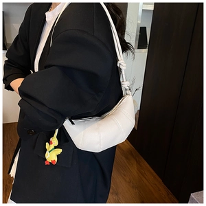 Close-up of white lychee texture leather croissant bag with stylish duck charm