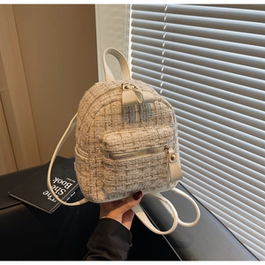 Détail d'un mini sac à dos en tweed avec tissage doré et languettes de fermeture en cuir