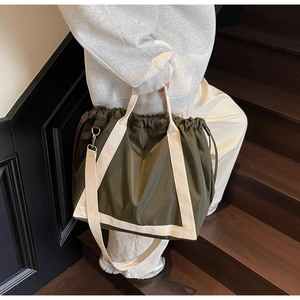 Detail of olive green nylon tote bag with drawstring closure and contrast straps