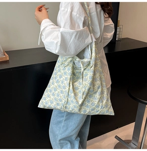 Détail d'un cabas en toile à fleurs avec motifs bleus et bretelles ornées de nœuds