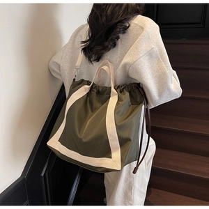 Olive green nylon tote bag featuring cream white webbing straps and drawstring closure