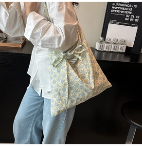 Détail du sac cabas floral avec motifs bleus, nœud papillon et petite étiquette latérale