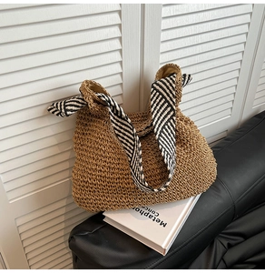 Détail du sac cabas en paille tissée avec des anses contrastées à rayures noires et blanches