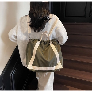 Detail of army green nylon tote bag with drawstring closure and off-white shoulder straps