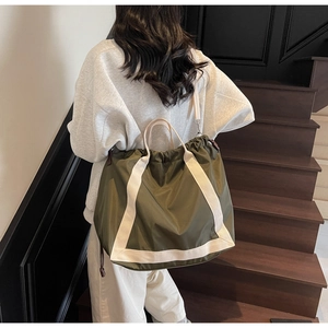 Detail of army green tote bag with contrast cream straps shown from a side view