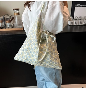 Détail du sac cabas floral avec motifs bleus et décoration de nœud en ruban latéral