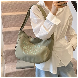 Détail du sac demi-lune en toile vert olive avec broderie Super Star et bandoulière large