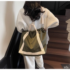Detail of olive green nylon tote bag with white canvas straps and drawstring closure
