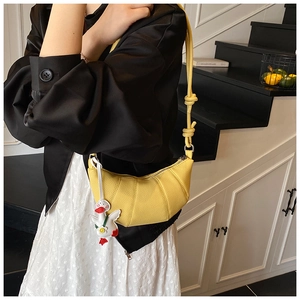 Detail of yellow pebbled leather croissant bag featuring a cute white duck charm