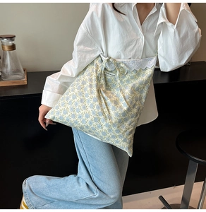 Détail d'un sac cabas en toile à fleurs avec bordure en dentelle et étiquette You're So Cute