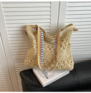 Détail d'un sac cabas en paille tressée avec motif floral ajouré et bandoulière jacquard