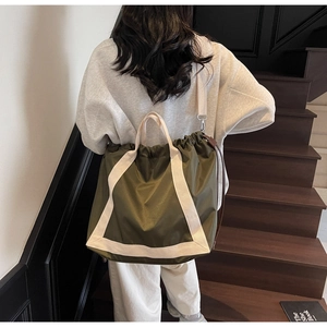 Rear view of casual olive green drawstring tote bag with off-white shoulder straps