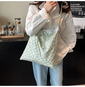 Détail d'un sac cabas floral avec motifs de fleurs bleues et bordure en dentelle blanche