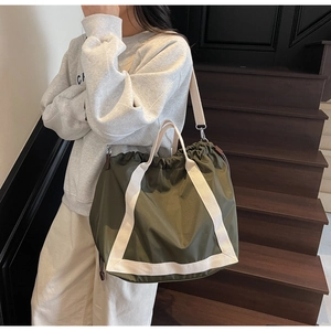 Detailed view of large olive green nylon tote bag with durable white woven handles