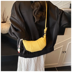 Detailed view of a bright yellow croissant-shaped crossbody bag in lychee pattern leather