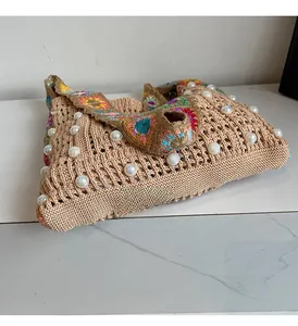 Detailansicht der beigen gewebten Tasche mit Perlen und farbenfrohem floralem Gurt