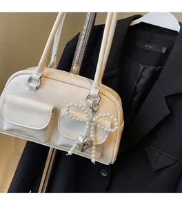 Close-up of off-white leather Boston bag featuring pearl bows and heart charms decoration