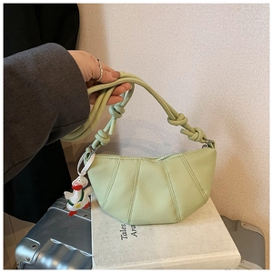 Close-up of light green lychee texture crescent bag with knotted strap and duck charm