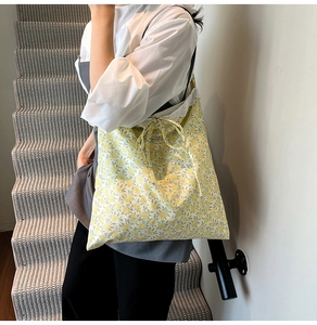Détail d'un sac cabas floral avec motif jaune, bordure en dentelle et nœud élégant