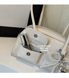 Close-up of white patent leather bag with front pocket for lipstick and pearl charms