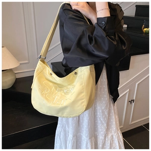 Détail du sac à bandoulière croissant jaune clair avec broderie Super Star et sangle