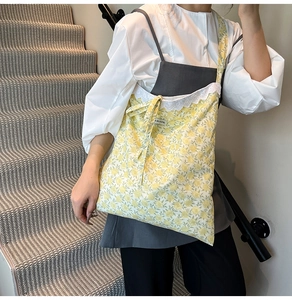 Détail d'un sac cabas floral jaune avec bordure en dentelle blanche et étiquette