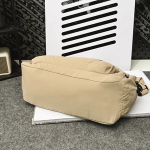 Detail view of khaki nylon dumpling bag showing reinforced stitching and adjustable strap buckle
