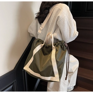 Detail of olive green nylon tote bag featuring drawstring closure and woven straps