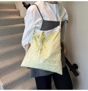 Détail du sac cabas en toile à fleurs jaunes avec bordure en dentelle et nœud