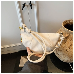 Detail of white crescent handbag showing pebbled leather texture and rope handle design