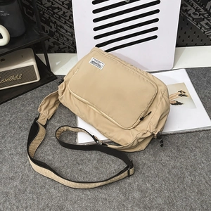 Close-up of khaki nylon dumpling bag featuring front zipper pocket and wide strap
